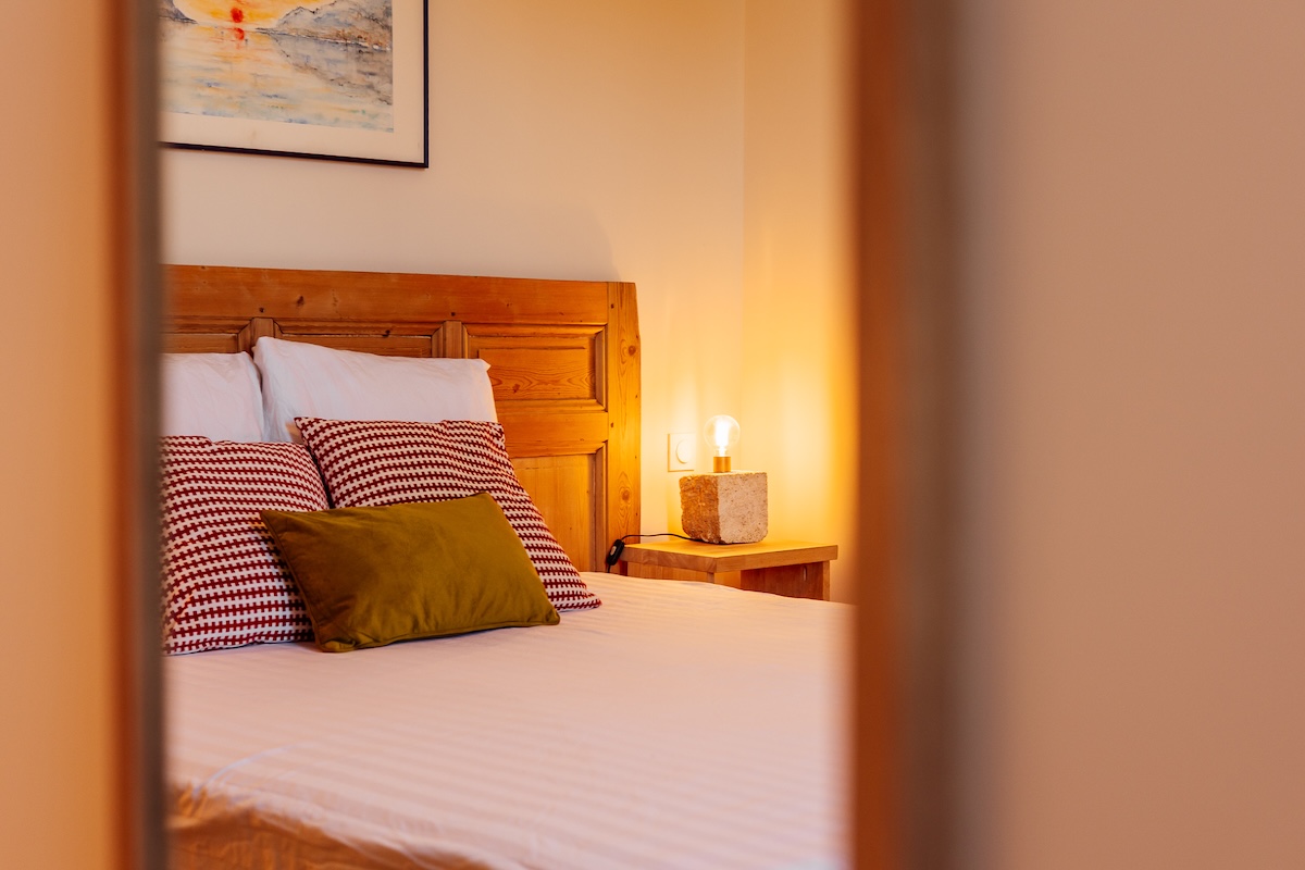 Tête de lit en bois, coussins en velours pour le gîte Effet de miroir dans la chambre aux couleurs moutarde et bordeaux ainsi que sa tête de lit en bois